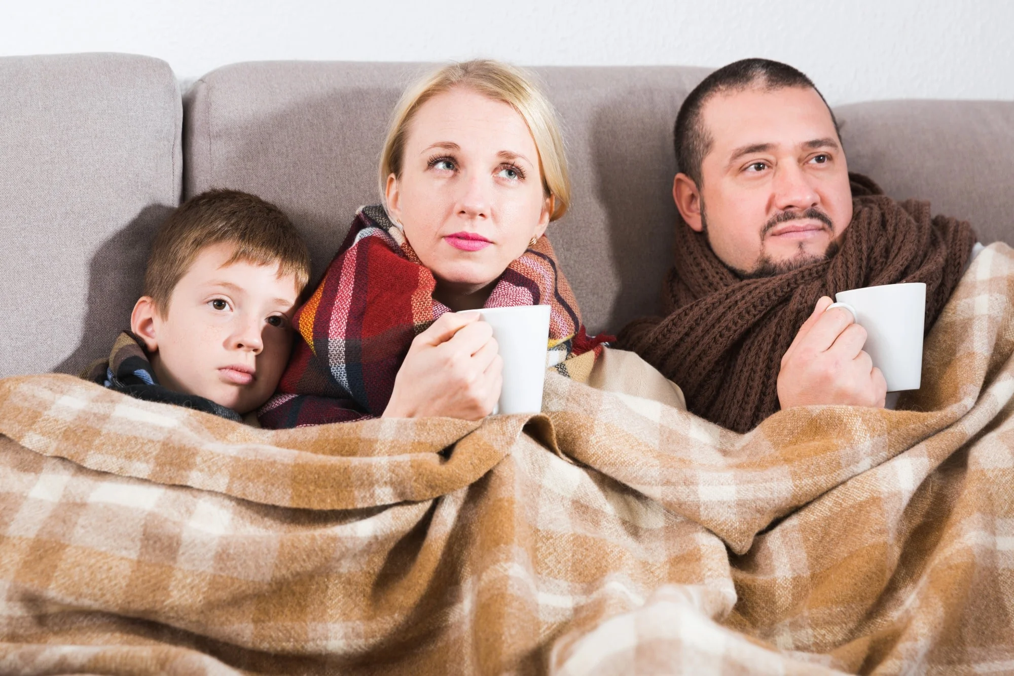 Family bundled in blankets and drinking hot beverages